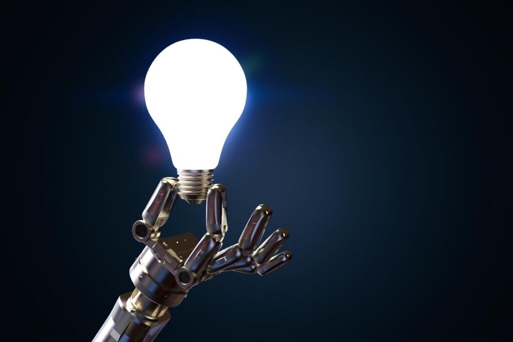 a robotic hand holding lit lightbulb - AI in Manufacturing